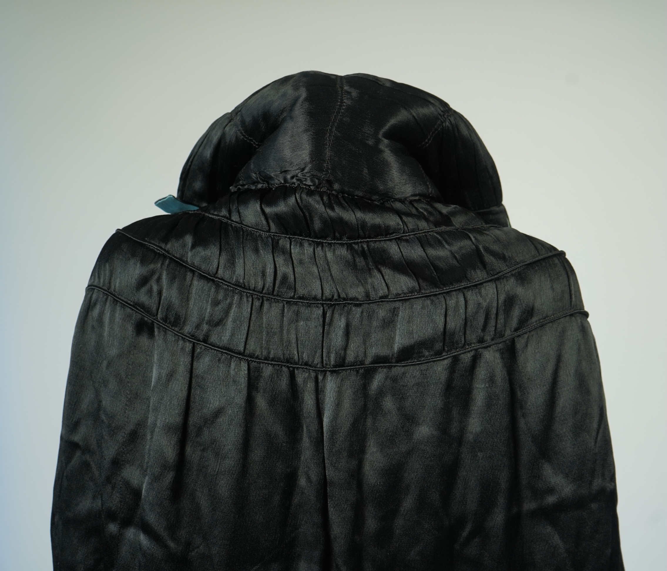 A 1920's ladies blue lined, black silk opera cape. Designed with a rushed ornate collar and scalloped and fringed lower edge. 95cm long fron neck to base. Condition - stained near the front edge, possibly removable with